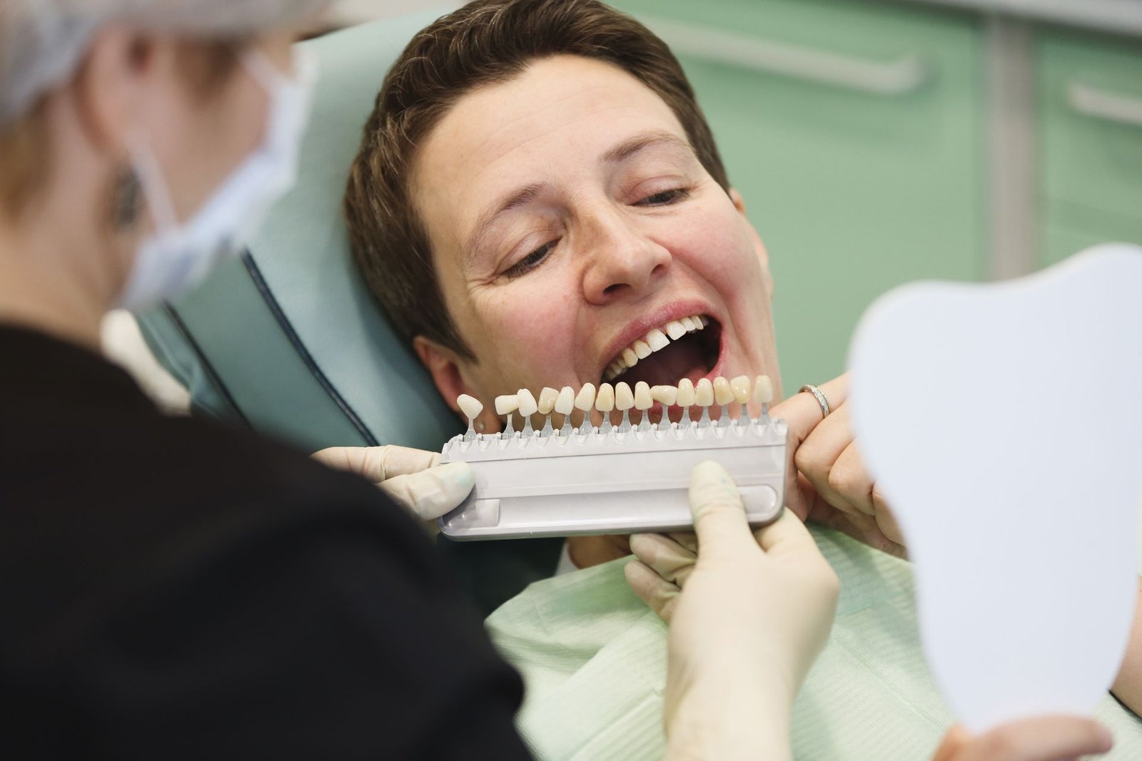 Valutazione del colore dei denti su una paziente in poltrona nello studio odontoiatrico